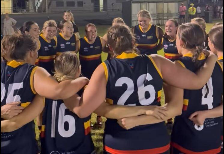 Leeton-Whitton's players belt out the team song after their maiden senior women's football win at Leeton Showground on Friday night.